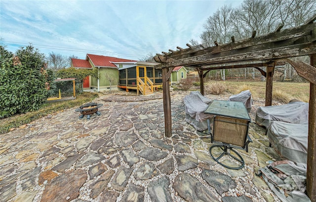 view of patio / terrace featuring a sunroom and a fire pit