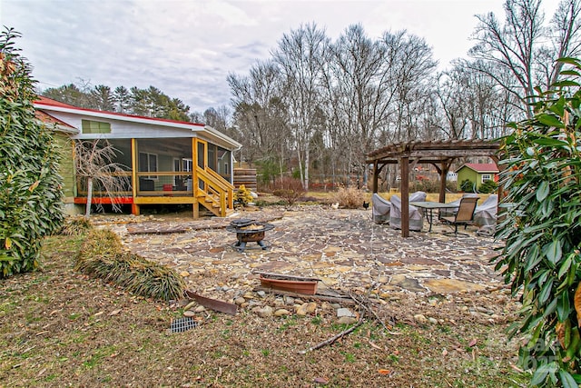 view of yard with an outdoor fire pit, a sunroom, a patio, and a pergola