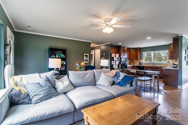 living area with recessed lighting, wood finished floors, a ceiling fan, and crown molding