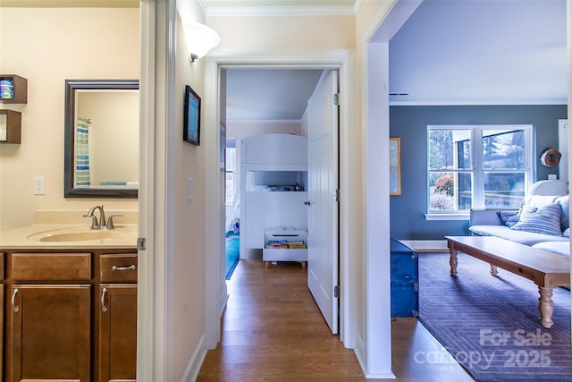 hall with crown molding, baseboards, dark wood finished floors, and a sink