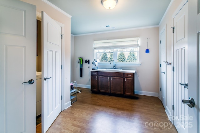 bathroom featuring vanity, baseboards, crown molding, and wood finished floors