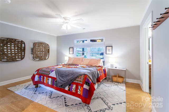 bedroom featuring baseboards, wood finished floors, and crown molding