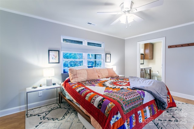 bedroom featuring baseboards, wood finished floors, visible vents, and crown molding