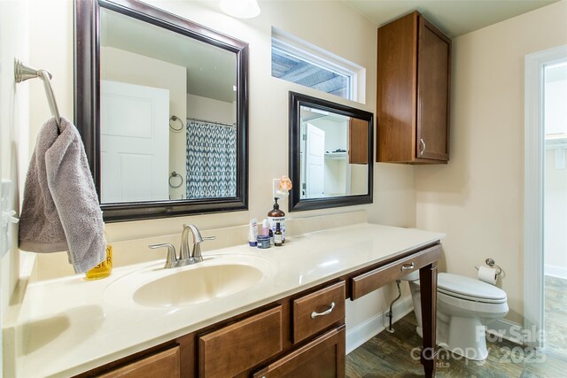 bathroom featuring toilet, baseboards, and vanity