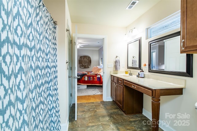 ensuite bathroom featuring visible vents, baseboards, a shower with curtain, stone finish flooring, and vanity