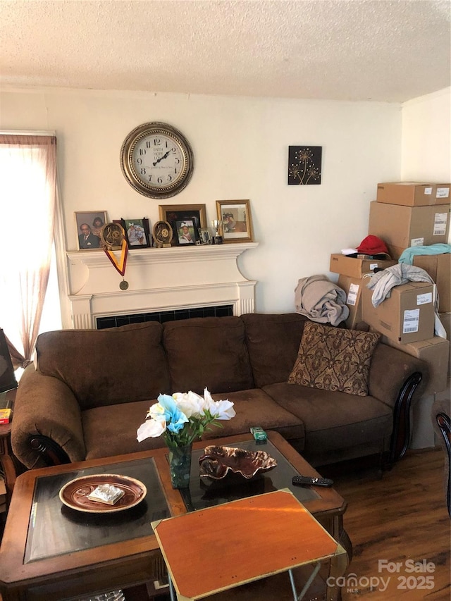 living room featuring a tiled fireplace, hardwood / wood-style floors, and a textured ceiling