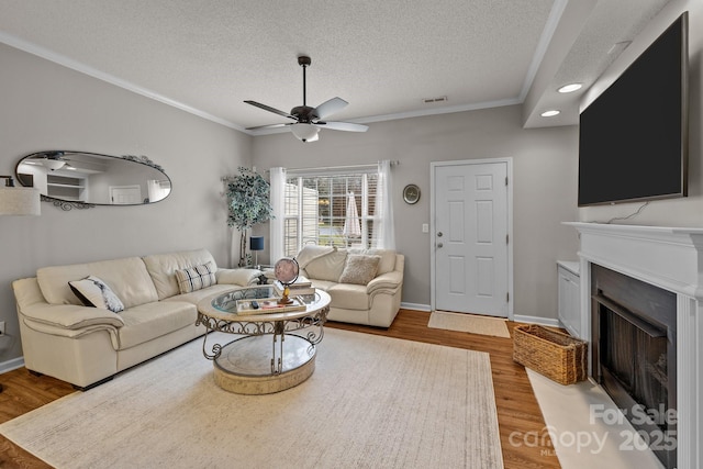 living room with hardwood / wood-style floors, crown molding, a textured ceiling, and ceiling fan