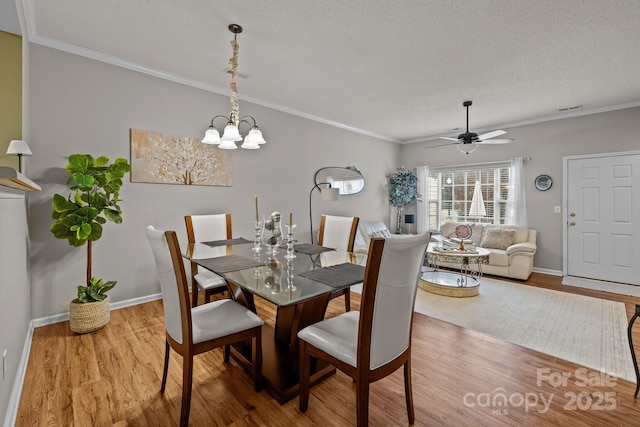 dining room with ceiling fan with notable chandelier, ornamental molding, a textured ceiling, and light wood-type flooring