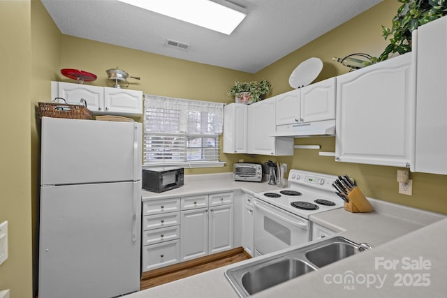 kitchen with white appliances, sink, a textured ceiling, and white cabinets