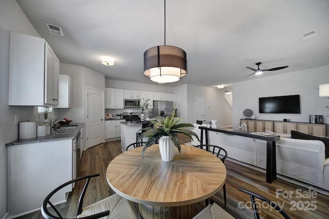 dining room featuring sink, dark wood-type flooring, and ceiling fan