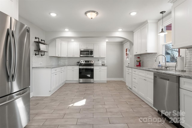 kitchen featuring sink, white cabinetry, light stone counters, hanging light fixtures, and stainless steel appliances