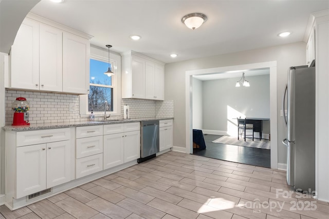 kitchen featuring sink, stainless steel appliances, decorative backsplash, white cabinets, and decorative light fixtures