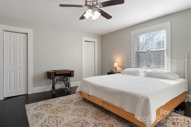 bedroom with dark hardwood / wood-style flooring, two closets, and ceiling fan