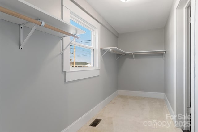 walk in closet featuring light colored carpet