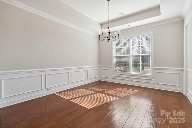 unfurnished room featuring dark wood-type flooring, ornamental molding, a tray ceiling, and a chandelier