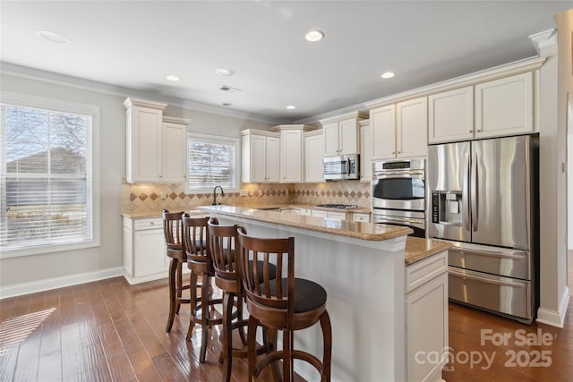 kitchen featuring dark wood-type flooring, sink, a center island, appliances with stainless steel finishes, and decorative backsplash