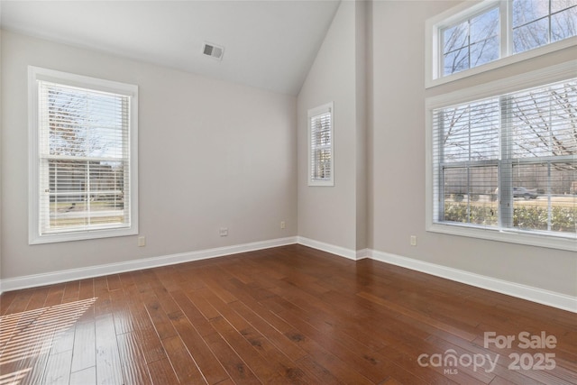 unfurnished room featuring a healthy amount of sunlight, lofted ceiling, and dark hardwood / wood-style floors