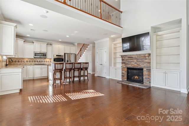 living room featuring crown molding, sink, dark wood-type flooring, and a fireplace