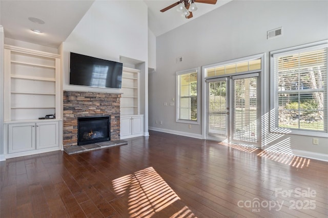 unfurnished living room with built in features, ceiling fan, high vaulted ceiling, dark hardwood / wood-style floors, and a fireplace