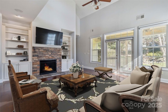 living room featuring high vaulted ceiling, built in features, ceiling fan, a fireplace, and hardwood / wood-style floors