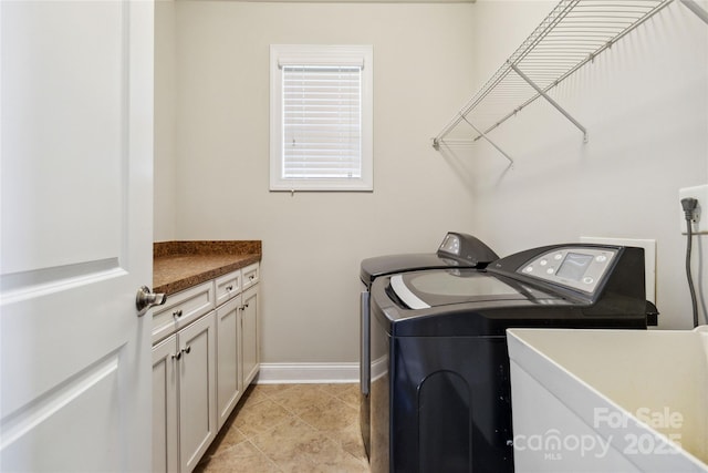 clothes washing area with cabinets, light tile patterned floors, and washer and dryer