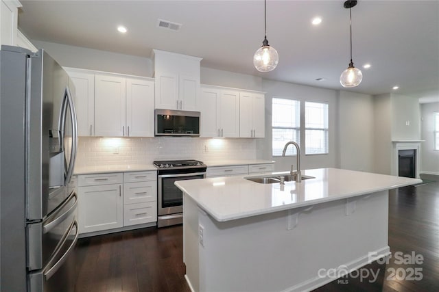 kitchen with appliances with stainless steel finishes, decorative light fixtures, sink, and white cabinets