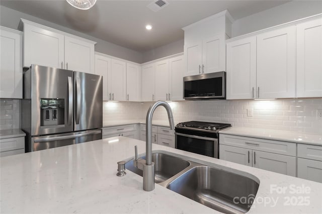 kitchen featuring light stone counters, white cabinetry, appliances with stainless steel finishes, and tasteful backsplash