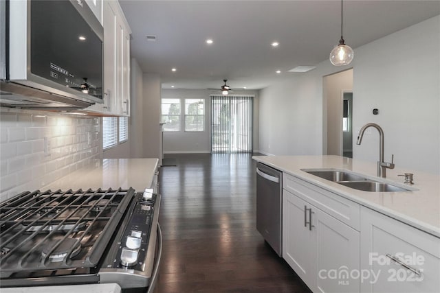 kitchen with sink, white cabinetry, hanging light fixtures, stainless steel appliances, and dark hardwood / wood-style flooring