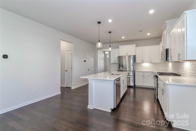 kitchen featuring a kitchen island with sink, hanging light fixtures, stainless steel appliances, and white cabinets