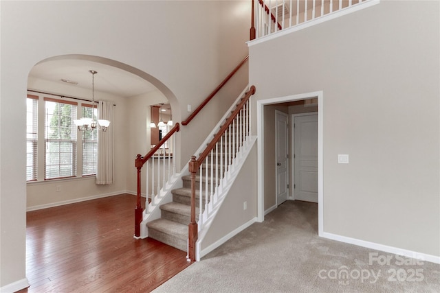 stairway featuring an inviting chandelier, hardwood / wood-style flooring, and a high ceiling