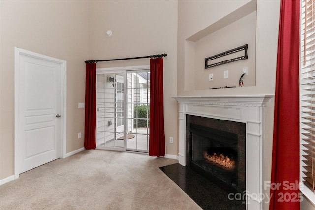 unfurnished living room featuring a towering ceiling and light colored carpet