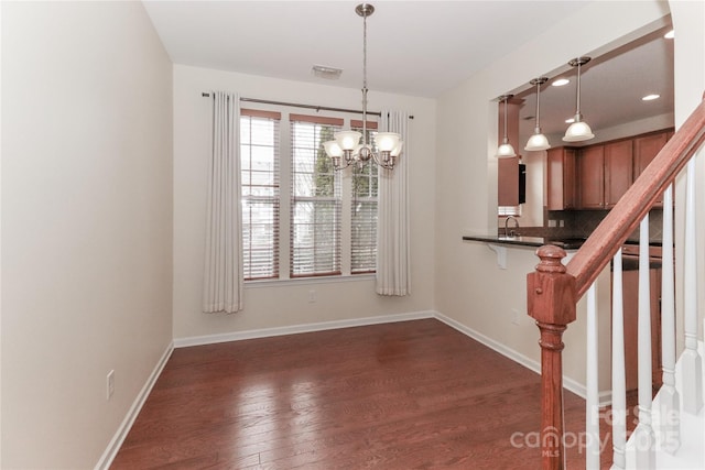 unfurnished dining area with an inviting chandelier, sink, and dark wood-type flooring