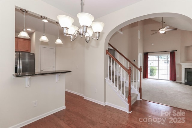 interior space featuring dark hardwood / wood-style flooring, ceiling fan with notable chandelier, and lofted ceiling