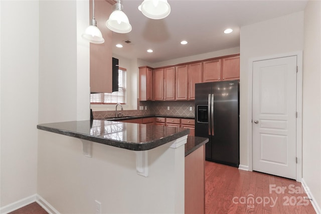 kitchen with pendant lighting, sink, fridge with ice dispenser, decorative backsplash, and kitchen peninsula