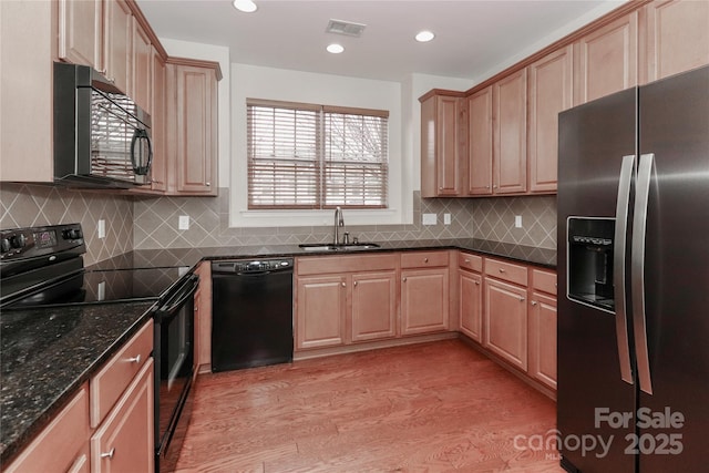 kitchen with sink, light hardwood / wood-style flooring, dark stone countertops, black appliances, and light brown cabinets