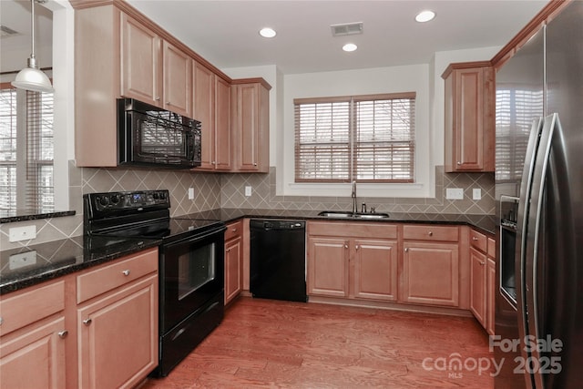 kitchen featuring sink, light hardwood / wood-style flooring, pendant lighting, decorative backsplash, and black appliances