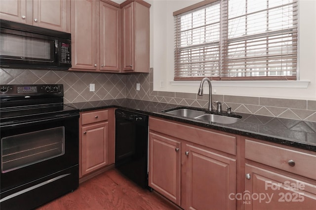 kitchen featuring sink, decorative backsplash, dark stone counters, black appliances, and light hardwood / wood-style flooring