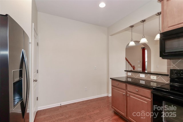 kitchen featuring pendant lighting, decorative backsplash, dark wood-type flooring, and black appliances