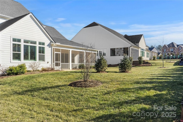 rear view of property with a sunroom and a lawn