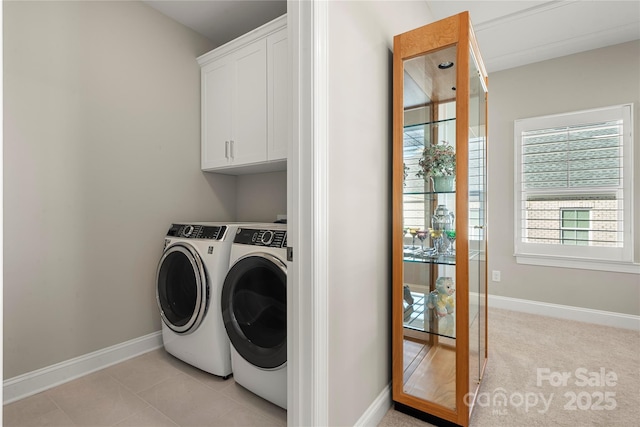 clothes washing area with light tile patterned floors, washing machine and dryer, and cabinets