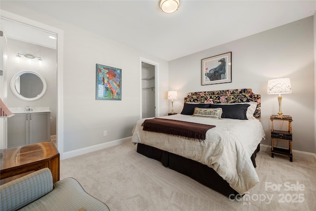 carpeted bedroom with a closet, sink, ensuite bath, and a spacious closet