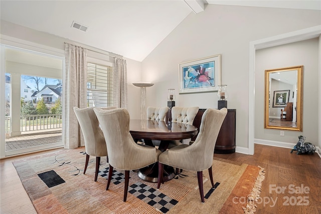 dining space featuring hardwood / wood-style flooring and vaulted ceiling with beams