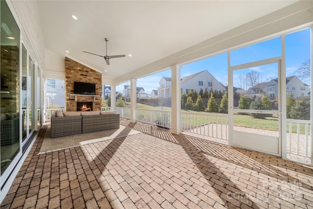 unfurnished sunroom featuring ceiling fan, lofted ceiling, a fireplace, and plenty of natural light