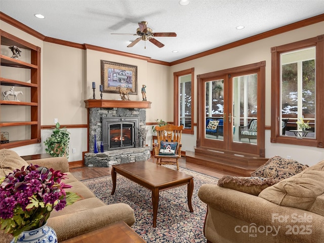 living room featuring a fireplace, wood-type flooring, ceiling fan, crown molding, and a textured ceiling