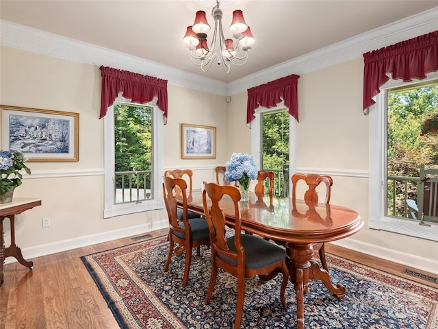 dining room featuring wood-type flooring, plenty of natural light, crown molding, and an inviting chandelier