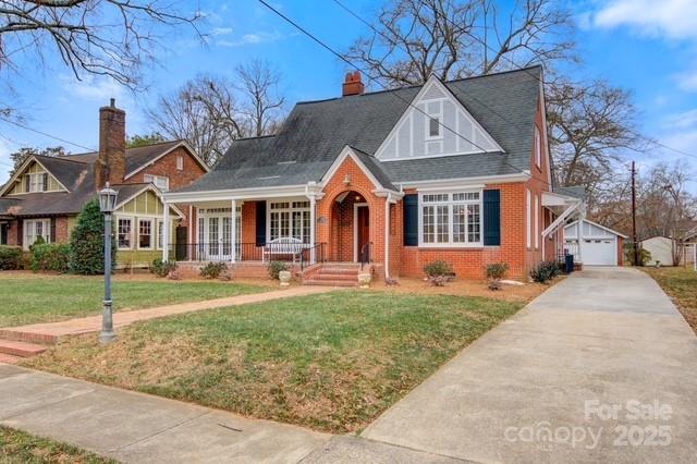 view of front of home with a garage, an outdoor structure, a front yard, and covered porch