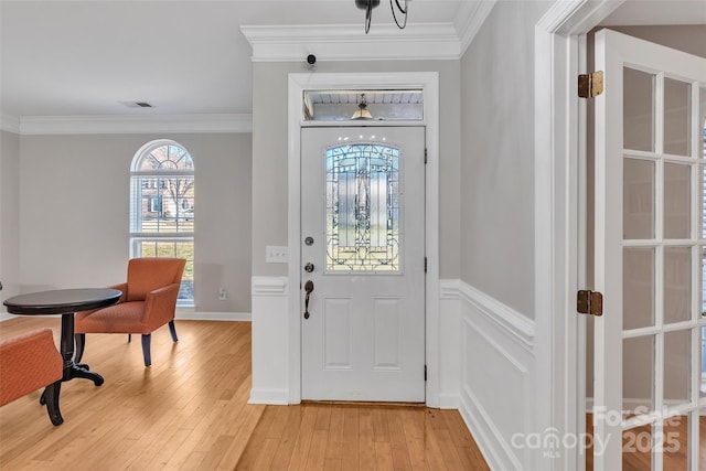 foyer entrance featuring crown molding and light hardwood / wood-style flooring