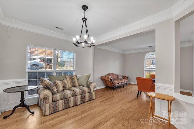 living room featuring an inviting chandelier, crown molding, and light wood-type flooring