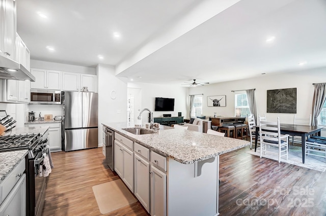 kitchen featuring sink, a breakfast bar area, white cabinetry, stainless steel appliances, and a kitchen island with sink