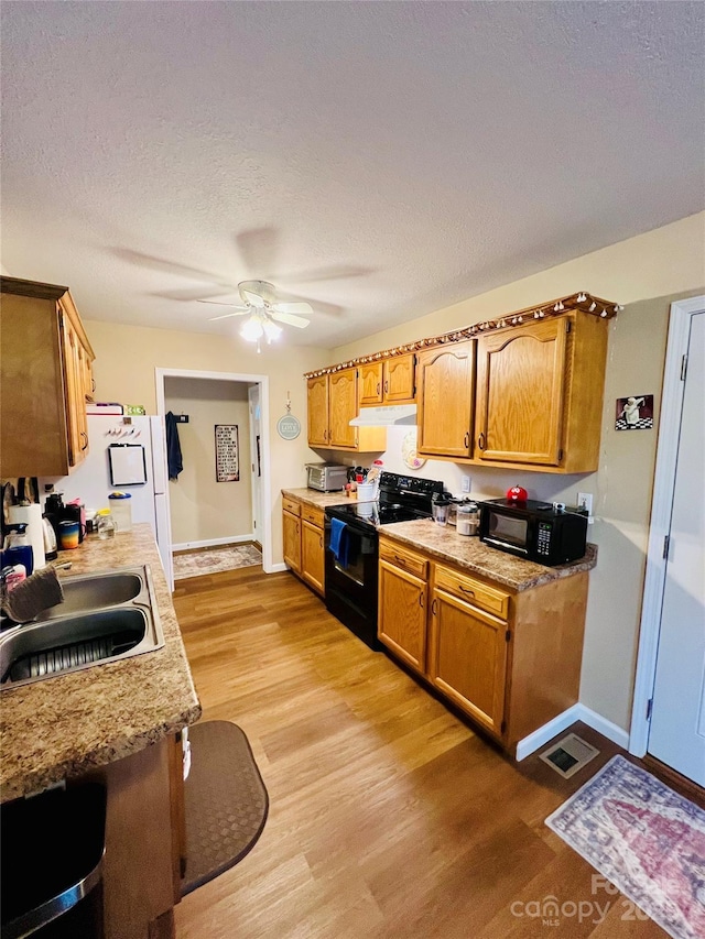 kitchen featuring sink, black appliances, light hardwood / wood-style floors, and ceiling fan